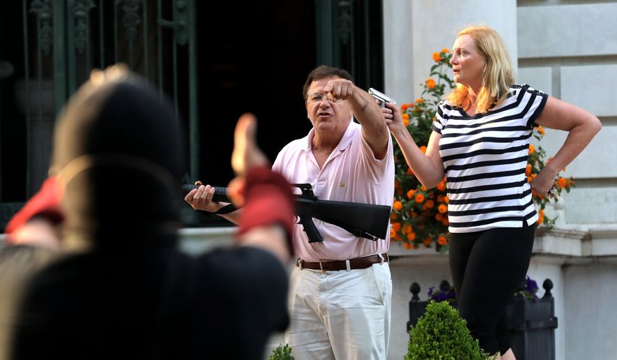Armed homeowners Mark and Patricia McCloskey, standing in front their house along Portland Place confront protesters marching to St. Louis Mayor Lyda Krewson&#39;s house in the Central West End of St. Louis. (Laurie Skrivan/St. Louis Post-Dispatch via AP File)