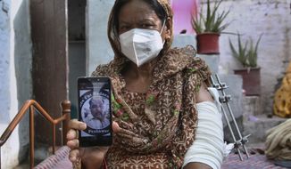 Elizabeth Lal, a Christian woman who was injured and her son-in-law Nadeem Jordon killed by gunmen because he rented in a Muslim neighborhood, shows a picture of Jordon on her mobile during an interview with the Associated Press, in Peshawar, Pakistan, Thursday, July 9, 2020. Analysts and activists say minorities in Pakistan are increasingly vulnerable to Islamic extremists as Prime Minister Imran Khan vacillates between trying to forge a pluralistic nation and his conservative Islamic beliefs. (AP Photo/Muhammad Sajjad)