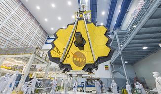 In this 2017 photo made available by NASA, technicians lift the mirror assembly of the James Webb Space Telescope using a crane inside a clean room at NASA&#39;s Goddard Space Flight Center in Greenbelt, Md. (Desiree Stover/NASA via AP) ** FILE **