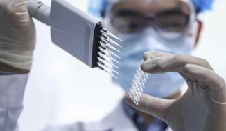 In this April 11, 2020, file photo, released by Xinhua News Agency, a staff member tests samples of a potential COVID-19 vaccine at a production plant of SinoPharm in Beijing. In the global race to make a coronavirus vaccine, the state-owned Chinese company is boasting that it gave its employees, including top executives, experimental shots even before the government OK&#39;d testing in people. (Zhang Yuwei/Xinhua via AP)