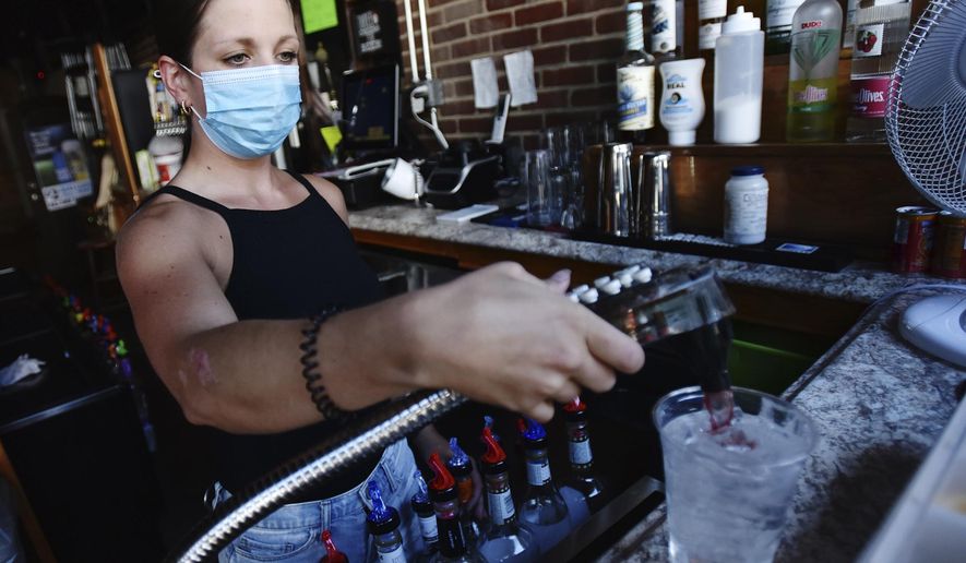 Bartender Kelsey Drozda makes a drink behind the bar at the Riverside Cafe in Wilkes-Barre, Pa., Wednesday, July 15, 2020. To fight the coronavirus, nightclubs will be shut down, bars will be closed unless they also offer dine-in meals, and bars and restaurants will be limited to 25% capacity under Gov. Tom Wolf's order, which takes effect Thursday and also requires companies to have their employees telework to the extent possible. (Sean McKeag/The Citizens' Voice via AP)