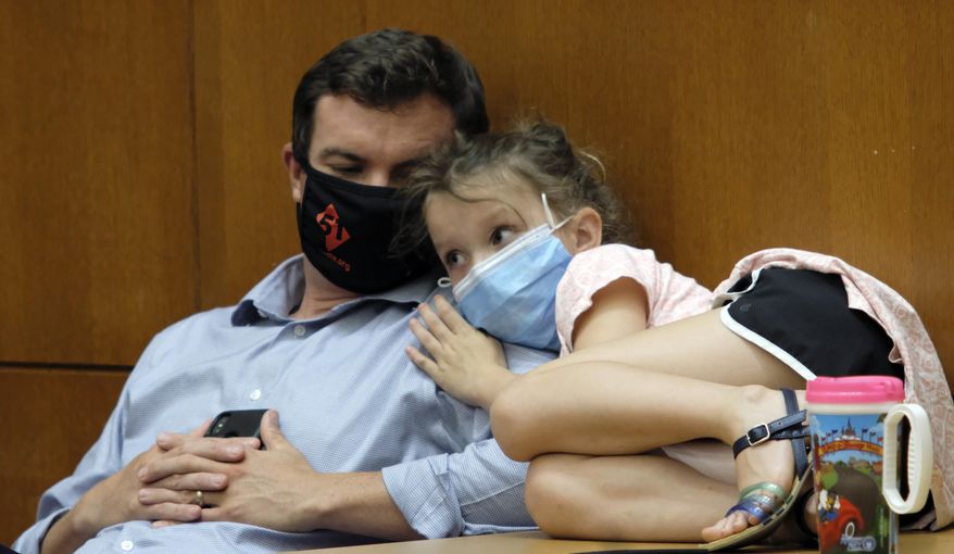 Chief of Staff Clarke Mercer and his daughter, Cecilia, 7, listen during Virginia Gov, Ralph Northam's press briefing inside the Patrick Henry Building in Richmond, Va., Tuesday, July 14,, 2020. (Bob Brown/Richmond Times-Dispatch via AP)