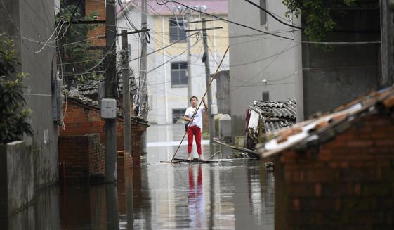 A woman pushes a makeshift raft down a flooded alleyway in a village in Yongxiu in central eastern China&#39;s Jiangxi province, Thursday, July 16, 2020. Engorged with more heavy rains, China&#39;s mighty Yangtze River is cresting again, bringing fears of further destruction. (Chinatopix via AP)