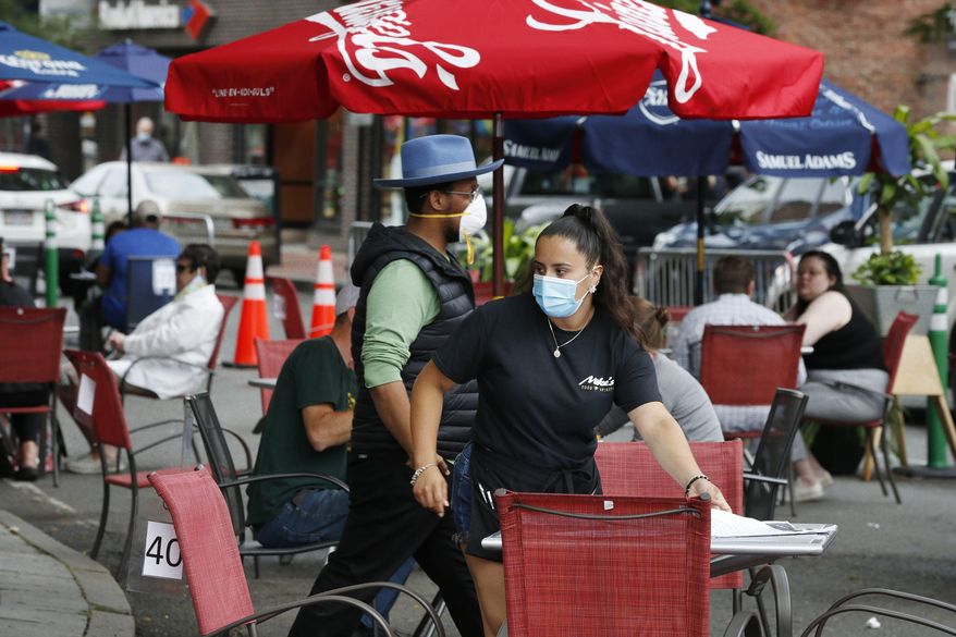 A waitress seats customers at a restaurant with outdoor dining on a section of street closed to traffic to promote social distancing, Friday, July 17, 2020, in Somerville, Mass. (AP Photo/Michael Dwyer)