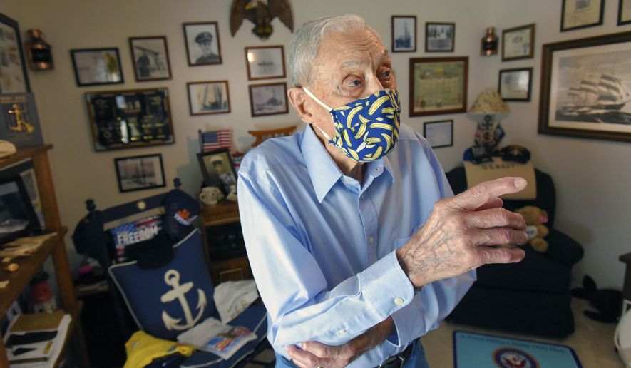 100 year old Bob Johnson gestures in the room of his home that contains photographs and mementos from his 20 year career in the U.S. Navy and his Antarctic explorations with Admiral Richard Byrd Tuesday, July 7, 2020 in Jacksonville, Fla. Robert Johnson, who turned 100 on Tuesday, a hot and sunny Florida day, barely hesitated when asked what he’d do if given another chance to go to Antarctica, the land of eternal ice and snow that he first journeyed to as a teenager. (Bob Self/The Florida Times-Union via AP)