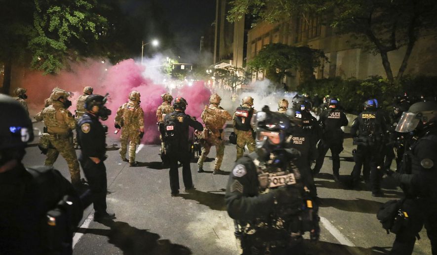 Police respond to protesters during a demonstration,  Friday, July 17, 2020 in Portland, Ore. Militarized federal agents deployed by the president to Portland, fired tear gas against protesters again overnight as the city’s mayor demanded that the agents be removed and as the state’s attorney general vowed to seek a restraining order against them. (Dave Killen/The Oregonian via AP)
