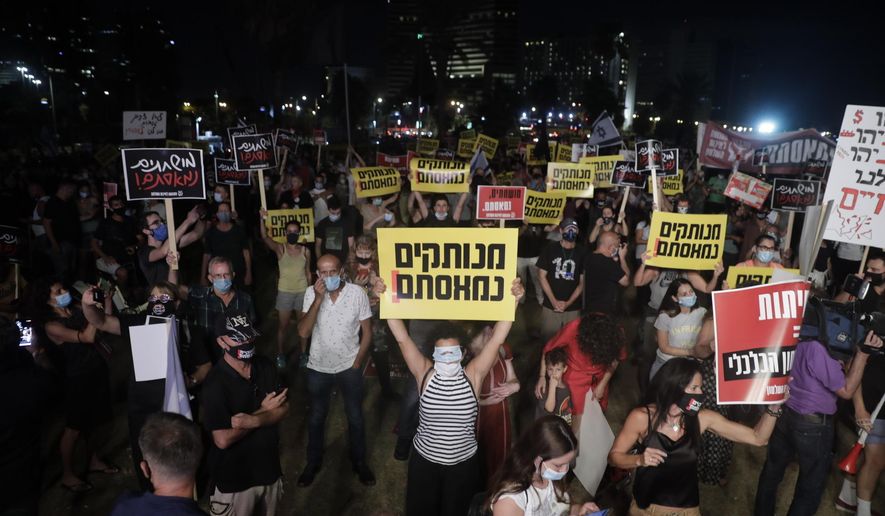 Israelis hold signs during a protest In Tel Aviv, Israel, Saturday, July 18, 2020. The sign says in Hebrew reads:"Out if touch, we are fed up." (AP Photo/Sebastian Scheiner)