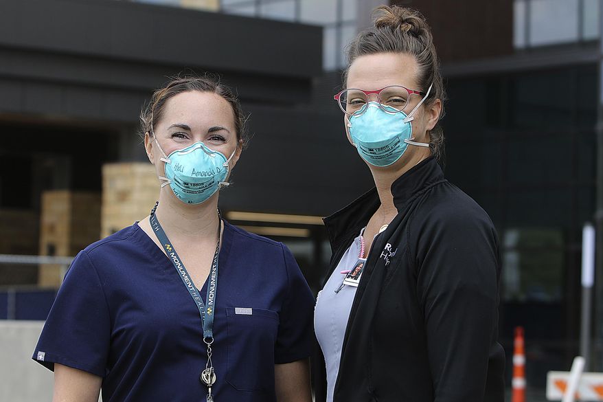 ADVANCE FOR PUBLICATION ON SATURDAY, JULY 18, AND THEREAFTER - Amanda Dosch, left, a registered nurse, and patient care champion Megan Cowan get ready to head back into their unit Friday, July 10, 2020, at Monument Health hospital in Rapid City, S.D., that treats patients who tested positive for COVID-19. (Jeff Eaton/Rapid City Journal via AP)