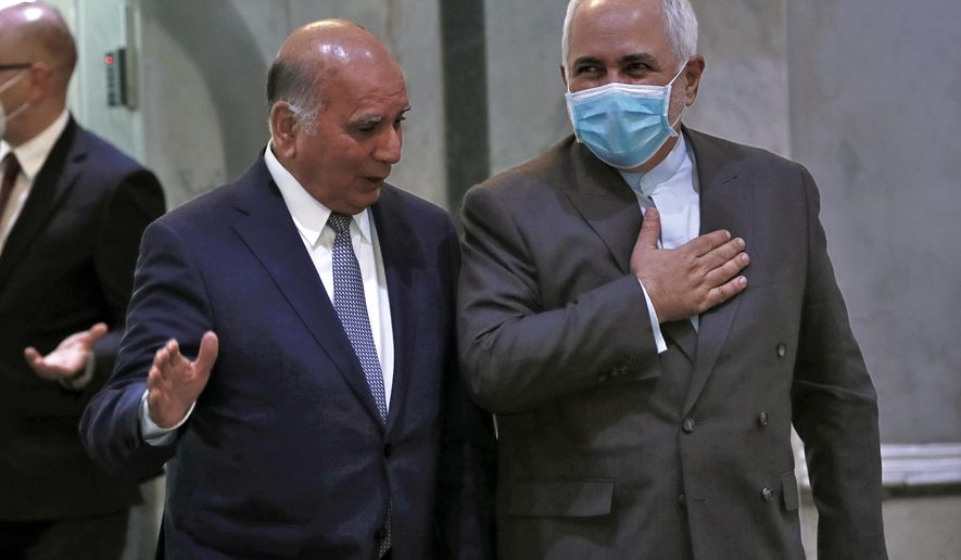 Iranian Foreign Minister, Mohammad Javad Zarif, right, wears a mask to help prevent the spread of the coronavirus walks with his Iraqi counterpart, Fouad Hussein during his visit to Baghdad, Iraq, Sunday, July 19, 2020. (AP Photo/Hadi Mizban)
