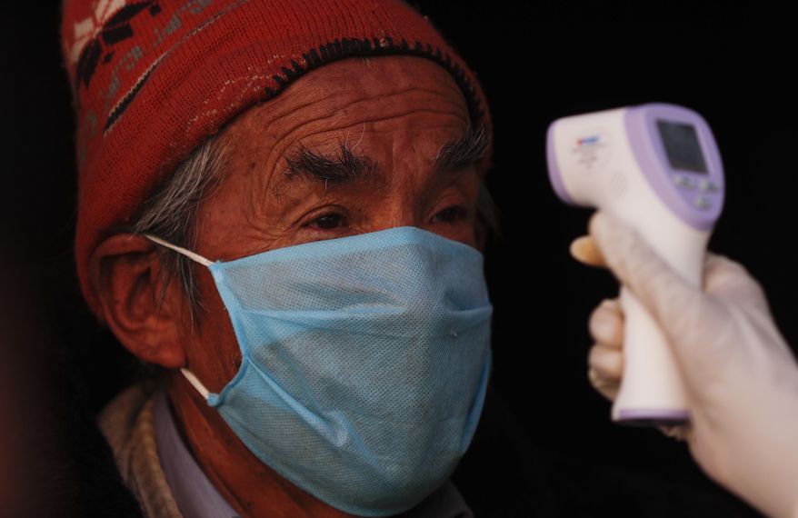 A resident stands still as a healthcare worker dressed in full protective gear measures his temperature during a new coronavirus testing drive in the Villa Dolores neighborhood of El Alto, Bolivia, Saturday, July 18, 2020. (AP Photo/Juan Karita)