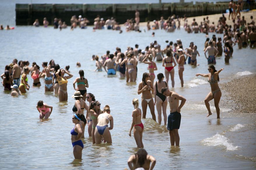 People gather on the beach, Saturday, July 18, 2020, in the South Boston neighborhood of Boston. Temperatures in the city reached into the 90's on Saturday. (AP Photo/Michael Dwyer)