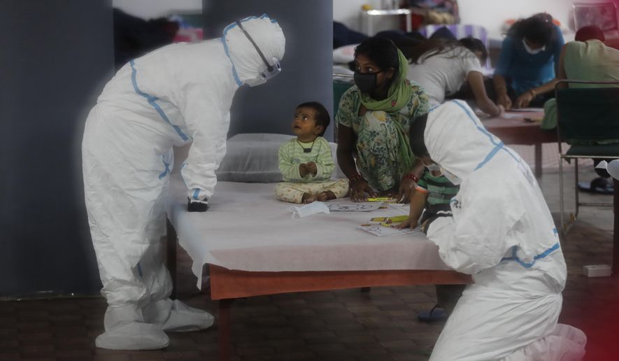 Doctors and health workers entertain children at a COVID-19 care center functioning in an indoor stadium in New Delhi, India, Monday, July 20, 2020. (AP Photo/Manish Swarup)