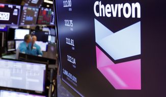 FILE - This Oct. 8, 2019, file photo the logo for Chevron appears above a trading post on the floor of the New York Stock Exchange. Chevron Corp. says it will acquire Noble Energy in an all-stock deal valued at $5 billion. The San Ramon, California-based Chevron has been shopping for an acquisition for months as oil prices have tanked due to the coronavirus outbreak.  (AP Photo/Richard Drew, File)
