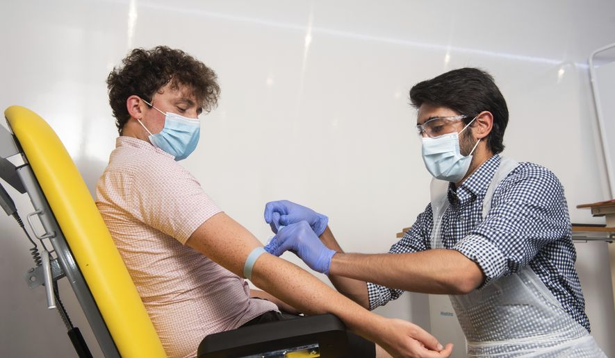 In this handout photo released by the University of Oxford, a doctor takes blood samples for use in a coronavirus vaccine trial in Oxford, England on Thursday, June 25, 2020. (John Cairns, University of Oxford via AP) ** FILE **