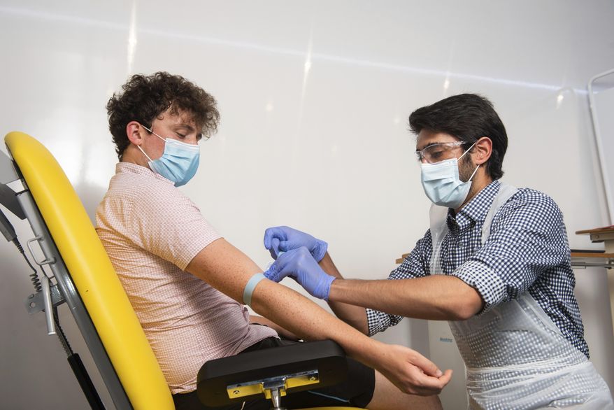 In this handout photo released by the University of Oxford, a doctor takes blood samples for use in a coronavirus vaccine trial in Oxford, England on Thursday, June 25, 2020. (John Cairns, University of Oxford via AP) ** FILE **