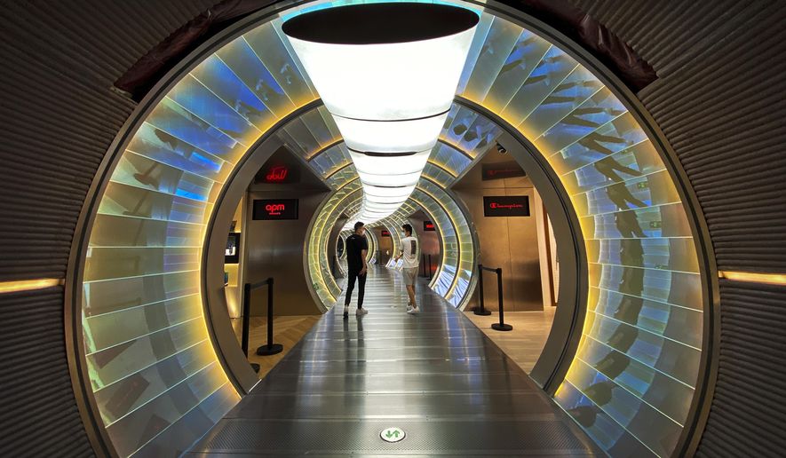 People wearing face masks to protect against the new coronavirus walk by a capsule shape shop lots inside a mall in Beijing, Monday, July 20, 2020. China's latest coronavirus outbreak has spread to a second city in the northwestern region of Xinjiang. (AP Photo/Andy Wong)