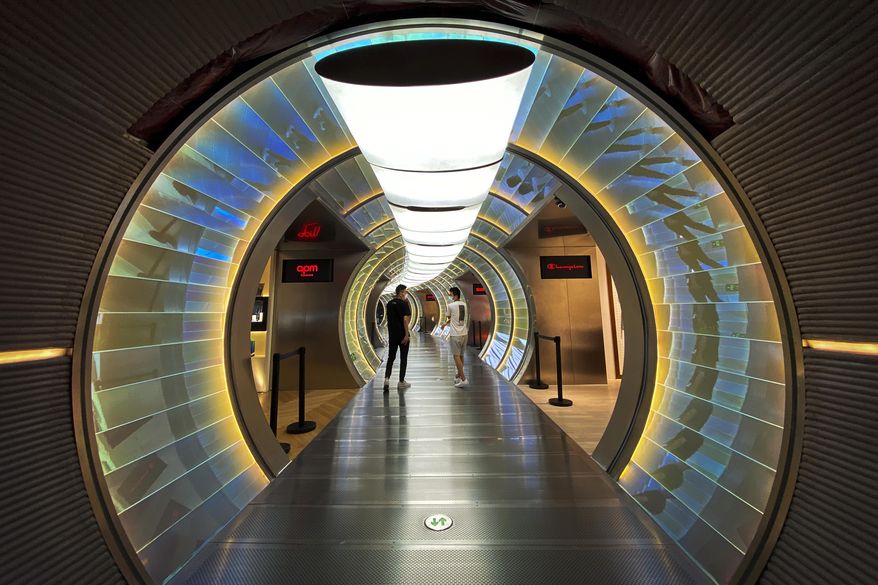 People wearing face masks to protect against the new coronavirus walk by a capsule shape shop lots inside a mall in Beijing, Monday, July 20, 2020. China's latest coronavirus outbreak has spread to a second city in the northwestern region of Xinjiang. (AP Photo/Andy Wong)