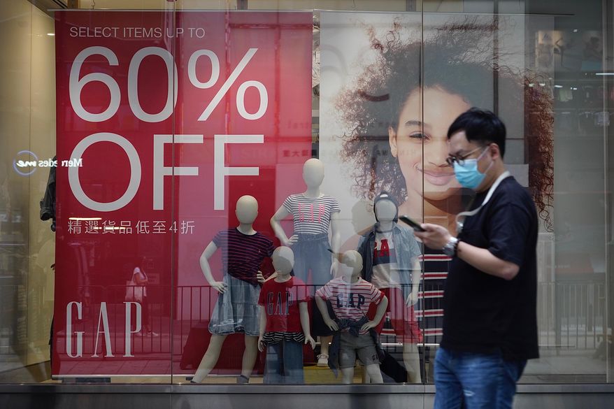 A man wearing a face mask to protect against the new coronavirus walks past a shop with sales discount sign in Hong Kong Tuesday, July 21, 2020. Hong Kong’s health officials said tighter anti-virus measures may be required if the new coronavirus infections do not come down over the next few days. (AP Photo/Vincent Yu)