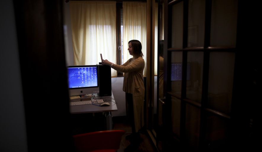 Psychologist Maria Clara Benitez text messages in the room where she attends patients online at her home during a government-ordered lockdown to curb the spread of the new coronavirus in Buenos Aires, Argentina, Monday, July 20, 2020. In the age of coronavirus, quarantine is posing a special challenge for residents of the world's most analyzed city. (AP Photo/Natacha Pisarenko)