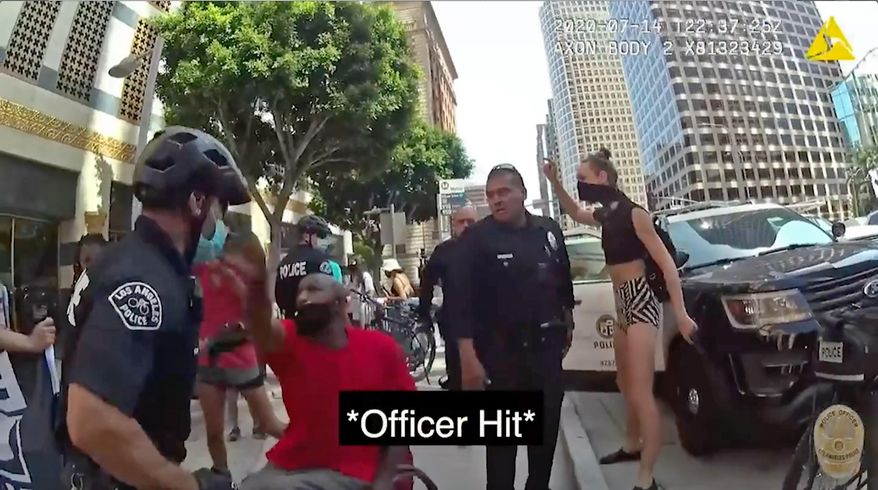 This Tuesday, July 14, 2020 photo from police body camera video released by the Los Angeles Police Department shows a confrontation between officers and a man in a wheelchair hitting an officer in the face in what authorities say prompted his arrest where he was knocked to the ground and out of his wheelchair amid a struggle. The incident occurred Tuesday and resulted in 33-year-old Joshua Wilson's arrest on suspicion of being a felon in possession of a firearm after authorities found a loaded gun in a backpack on his wheelchair. The video does not show Wilson ever reaching for his bag. (Los Angeles Police Department via AP)