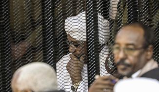 FILE - In this Aug. 24, 2019 file photo, Sudan&#39;s autocratic former President Omar al-Bashir sits in a cage during his trial on corruption and money laundering charges, in Khartoum, Sudan. On Tuesday, July 21, 2020, al-Bashir is back in court, this time facing charges of plotting the 1989 Islamist-backed coup that removed an elected government and brought him to power. The trial adjourned until Aug. 11. (AP Photo, File)