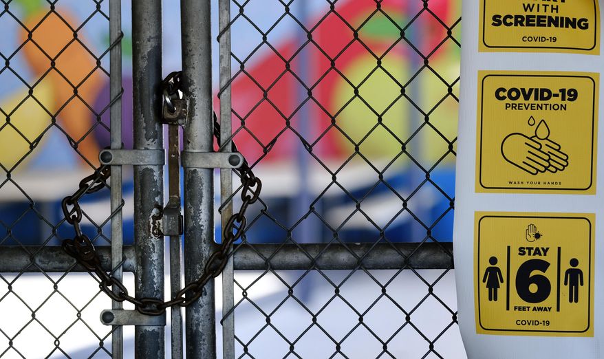 FILE - In this July 13, 2020 file photo, a chain-link fence lock is seen on a gate at a closed Ranchito Elementary School in the San Fernando Valley section of Los Angeles. While many California school districts are planning to start the upcoming school year with online instruction, some are also offering child care programs that will bring students onto otherwise quiet campuses. (AP Photo/Richard Vogel, file)