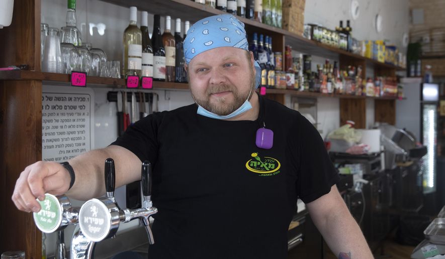 Cijay Brightman speaks during an interview with the Associated Press in Tel Aviv, Israel, Monday, July 13, 2020. A year ago, Brightman was doing sound and lighting for a Madonna performance in Israel. Now, after the coronavirus has wiped out live events, he's making sandwiches, slicing cheese and serving customers at a Tel Aviv deli. (AP Photo/Sebastian Scheiner)