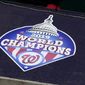 A 2019 World Series champions logo displayed is seen on the top of the dugout during the Washington Nationals baseball practice at Nationals Park, Wednesday, July 22, 2020, in Washington. (AP Photo/Nick Wass)