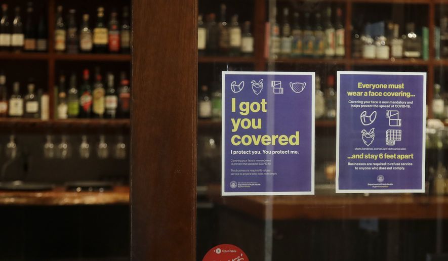 Signs advising social distancing and wearing face masks are posted on a door of The Barrel Room restaurant during the coronavirus outbreak in San Francisco, Tuesday, July 14, 2020. The Barrel Room, a San Francisco wine bar and restaurant, cautiously reopened last week, hoping to salvage as much of 2020 as possible from the coronavirus pandemic and the lockdowns meant to contain it. (AP Photo/Jeff Chiu) ** FILE **