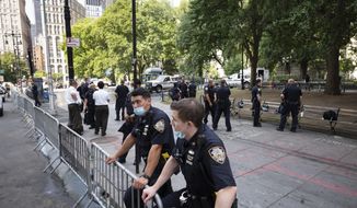Police stand behind barricades at a park adjacent to City Hall, Wednesday, July 22, 2020, in New York. Police in riot gear cleared a month-long encampment of protesters and homeless people from the park earlier in the morning. (AP Photo/Mark Lennihan)