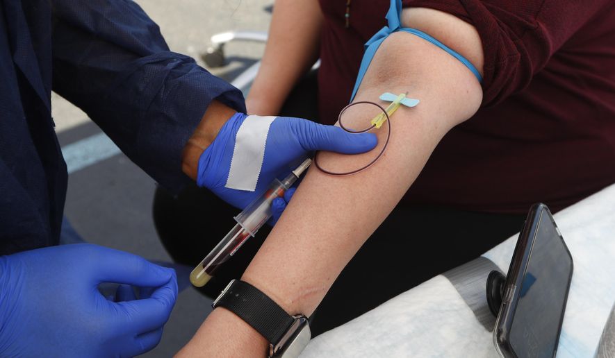 FILE - In this Friday, June 12, 2020 file photo, a woman has blood drawn for COVID-19 antibody testing in Dearborn, Mich. Research published on Tuesday, July 21, 2020 suggests that antibodies the immune system makes to fight the new coronavirus may only last a few months in people with mild illness. (AP Photo/Paul Sancya)