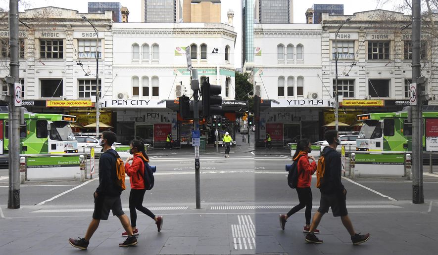 People wearing face masks to help protect against the spread of the new coronavirus walk in the central business district in Melbourne, Australia, Wednesday, July 22, 2020. Australia’s hard-hit Victoria state reported a record new COVID-19 cases on Wednesday and health authorities warned that numbers could continue to rise. With Australia’s second-largest city Melbourne now in lockdown for two weeks, authorities had hoped the infection rate would begin to plateau. (James Ross/AAP Image via AP)