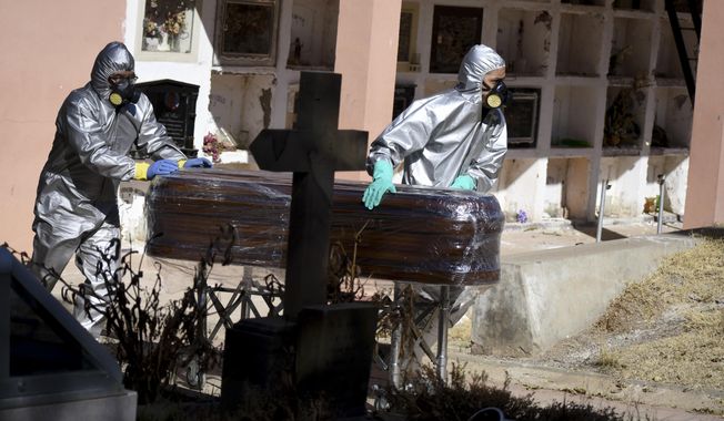 A plastic wrapped coffin containing the remains of Cristobal Huanca Mendoza is guided by workers through a cemetery to a common grave area, in Cochabamba, Bolivia, Thursday, July 2, 2020. Bolivia&#x27;s Institute of Forensic Investigations said that nationally from April 1 through July 19, its workers had recovered 3,016 bodies of people in possible COVID-19 cases. (AP Photo/Dico Soliz)