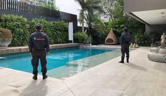 In this photo distributed by Colombia&#39;s Attorney Generals Office, officials pose with their backs to the camera by a pool on a property allegedly belonging to Alex Saab in Barranquilla, Colombia, Wednesday, July 22, 2020. Authorities seized a luxury mansion allegedly belonging to the businessman detained in Cape Verde on U.S. corruption charges related to Venezuelan President Nicolás Maduro. (Colombia&#39;s Attorney Generals Office via AP)