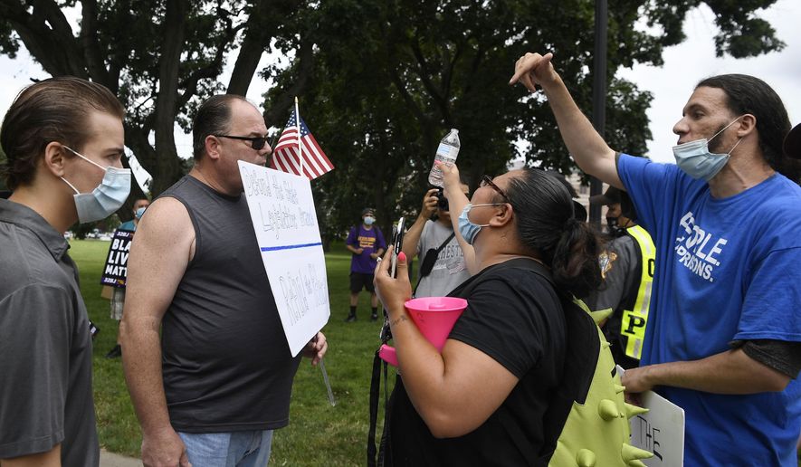 A man holding a sign reading Defund the State Legislative Branch, Refund the Police, second from left, is confronted by people supporting Black Lives Matter outside the State Capitol, Thursday, July 23, 2020, in Hartford, Conn. (AP Photo/Jessica Hill)