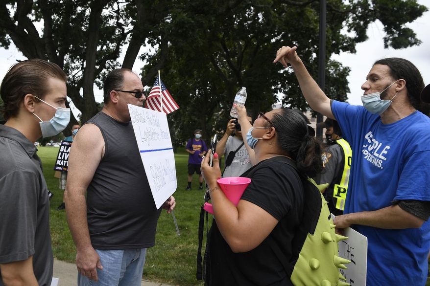 A man holding a sign reading Defund the State Legislative Branch, Refund the Police, second from left, is confronted by people supporting Black Lives Matter outside the State Capitol, Thursday, July 23, 2020, in Hartford, Conn. (AP Photo/Jessica Hill)