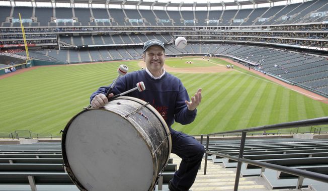 FILE - In this April 27, 2011, file photo, Cleveland Indians fan John Adams poses in his usual centerfield bleacher seat with his ever-present bass drum before a baseball game between the Indians and the Kansas City Royals in Cleveland. Adams, who will miss his first home opener since 1955 on Friday due to the coronavirus, has been keeping the beat for the Indians since 1973.  AP Photo/Amy Sancetta, File)