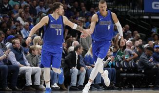 FILE - In this Oct. 27, 2019, file photo, Dallas Mavericks&#x27; Luka Doncic (77) and Kristaps Porzingis (6) celebrate a basket by Porzingis in the second half of an NBA basketball game against the Portland Trail Blazers in Dallas. The NBA restart means Doncic and  Porzingis are all but assured of making their playoff debuts in their first season on the court together with Dallas. (AP Photo/Tony Gutierrez, File)