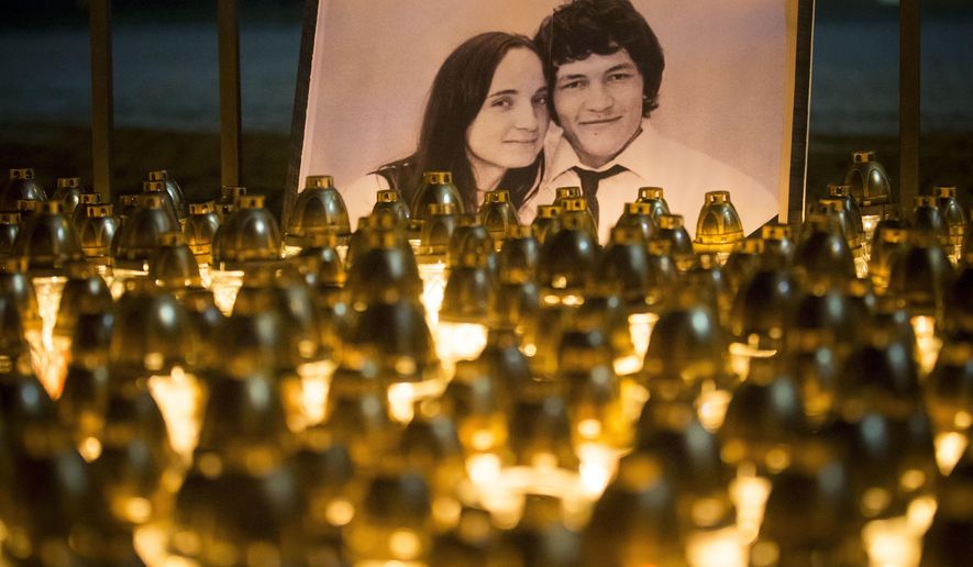 FILE - In this Wednesday, Feb. 28, 2018 file photo, light tributes are seen during a silent protest in memory of murdered journalist Jan Kuciak and his girlfriend Martina Kusnirova, seen in photo, in Bratislava, Slovakia. The state prosecutor in Slovakia requested on Thursday, July 23, 2020 a 25-year prison term for all three defendants in the alleged contract killings of an investigative journalist and his fiancee, a case that triggered a political crisis and brought down the country’s government. (AP Photo/Bundas Engler, file)