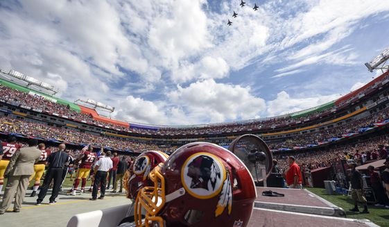 FILE - In this Sept. 18, 2016, file photo, F-26 fighter jets from the DC Air National Guard fly over FedEx Field before an NFL football game against between the Washington Redskins and the Dallas Cowboys in Landover, Md. A person with knowledge of the move tells The Associated Press the team formerly known as Redskins will go by Washington Football Team until a new name is chosen. Washington will keep its burgundy and gold colors and replace the Indian head logo on helmets with a player&#39;s jersey number.  (AP Photo/Nick Wass, File)