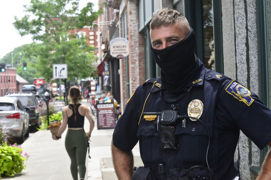 Brattleboro, Vt., Police Officer Jason Hamilton patrols around Brattleboro while wearing a mask on Friday, July 24, 2020. Vermont Gov. Phil Scott said in a press conference that starting Aug. 1, masks will be mandatory in public. (Kristopher Radder/The Brattleboro Reformer via AP)