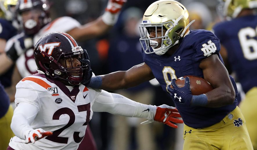 FILE - In this Nov. 2, 2019, file photo, Notre Dame running back Jafar Armstrong (8) stiff arms Virginia Tech linebacker Rayshard Ashby (23) during the second half of an NCAA college football game in South Bend, Ind. The Atlantic Coast Conference and Notre Dame are considering whether the Fighting Irish will give up their treasured football independence for the 2020 season play as a member of the league. (AP Photo/Carlos Osorio, File)