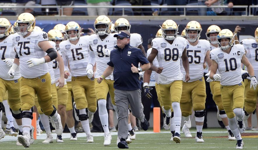 FILE - In this Dec. 28, 2019, file photo, Notre Dame head coach Brian Kelly, center, runs onto the field with his players before the Camping World Bowl NCAA college football game against Iowa State in Orlando, Fla. The Atlantic Coast Conference and Notre Dame are considering whether the Fighting Irish will give up their treasured football independence for the 2020 season play as a member of the league. (AP Photo/Phelan M. Ebenhack, File)