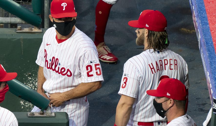 Philadelphia Phillies manager Joe Girardi, left, talks with Bryce Harper, right, prior to a baseball game against the Miami Marlins, Friday, July 24, 2020, in Philadelphia. (AP Photo/Chris Szagola)