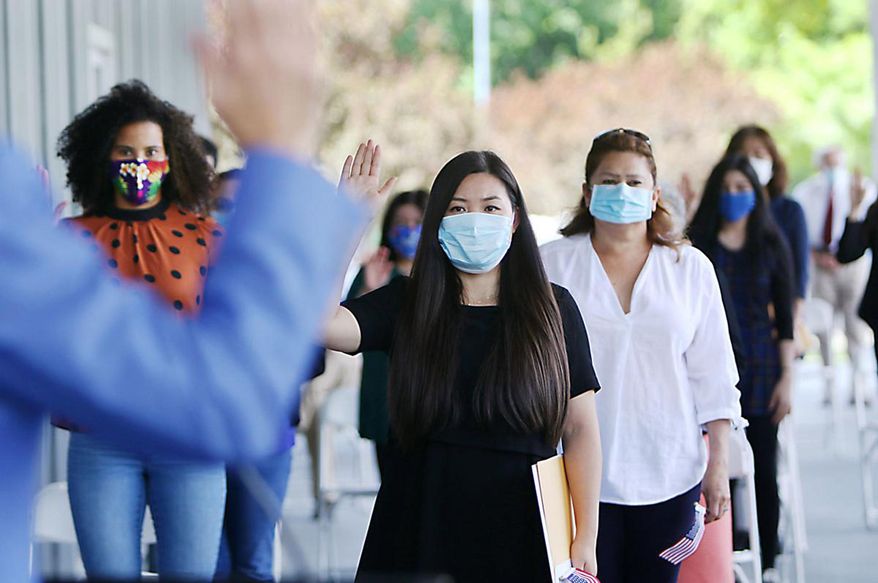New U.S. citizens are sworn in during a ceremony outside the James D. McClure U.S. Courthouse and Federal Building in downtown Boise, Idaho, on Thursday, July 23, 2020. An Idaho federal judge has held a rare outdoor court proceeding to swear in new U.S. citizens amid the coronavirus pandemic. The Idaho Press reports that U.S. Magistrate Judge Candy Dale swore in 37 people from 14 countries. (Brian Myrick/The Idaho Press via AP)