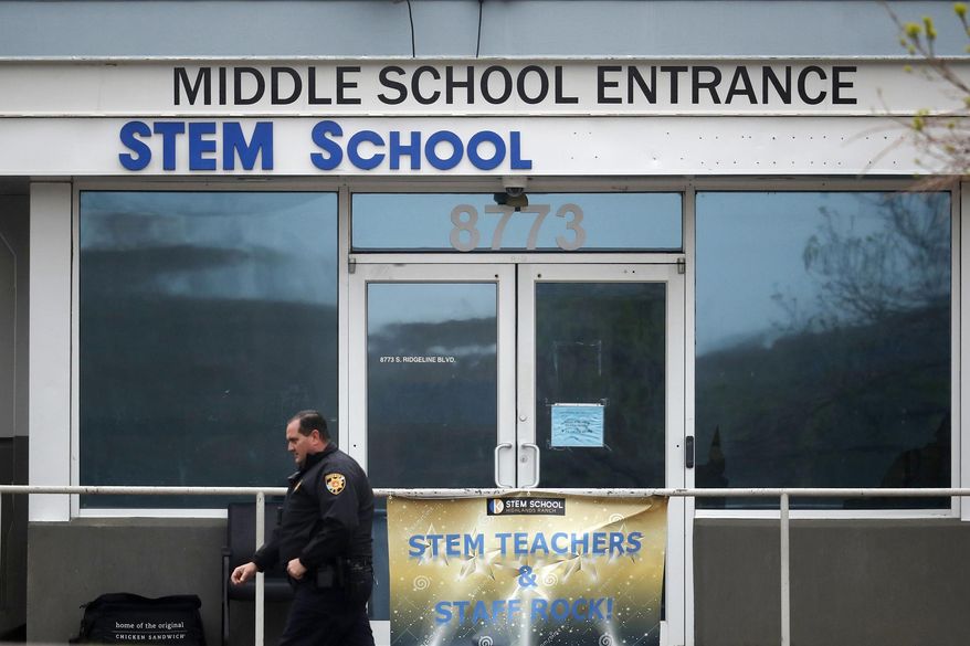 FILE - In this May 8, 2019, file photo, a Douglas County, Colo., Sheriff's deputy walks past the doors of the STEM Highlands Ranch school in Highlands Ranch, Colo. The younger of two students charged in the shooting at the suburban Denver school in the spring of 2019 is scheduled to be sentenced Friday, July 24, 2020. The decision will come after a hearing in which those impacted by the shooting, including the parents of a student who died trying to stop the attack at STEM School Highlands Ranch, will speak. (AP Photo/David Zalubowski, File)