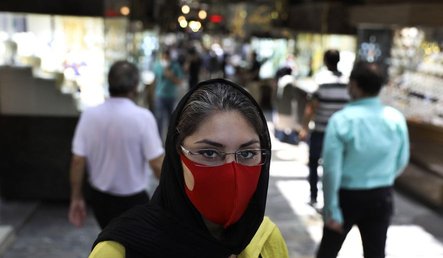 Reyhane Rajaei wearing a protective face mask to help prevent the spread of the coronavirus speaks with The Associated Press at a gold market of Tehran's Grand Bazaar, Iran, Wednesday, July 22, 2020. "My own grandmother died from the new coronavirus, and some members of may family also caught it but they survived. I try to wear a face mask so that I won't catch it at least and also to avoid putting other into trouble." Reyhane said. (AP Photo/Vahid Salemi)