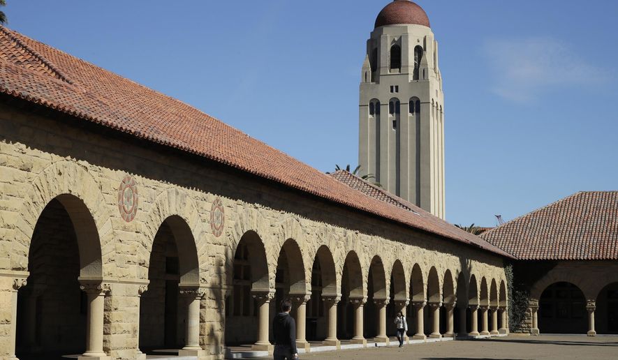 FILE- In this March 14, 2019, file photo, people walk on the Stanford University campus beneath Hoover Tower in Stanford, Calif. A week after revoking sweeping new restrictions on international students, federal immigration officials on Friday, July 24, 2020, announced that new foreign students will be barred from entering the United States if they plan to take their classes entirely online this fall. (AP Photo/Ben Margot, File)