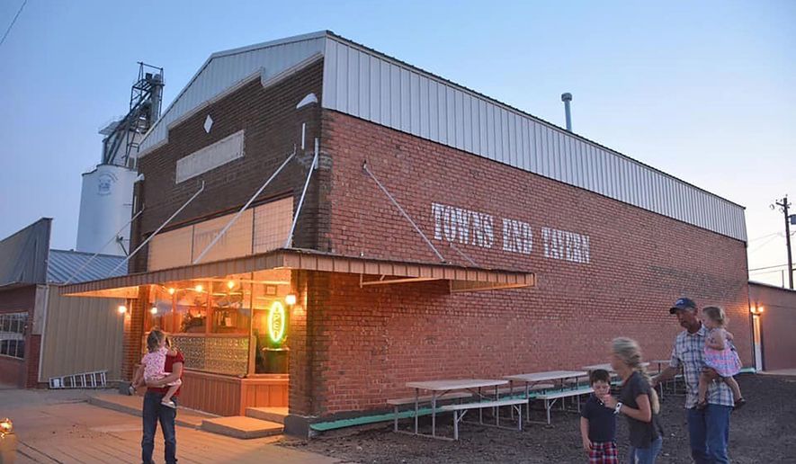 In this photo provided by tavern owner Erin Wright, people gather outside the Towns End Tavern in Sharon Springs, Kan., Wednesday, July 22, 2020. The tavern isn't requiring customers to wear masks, but it is asking questions about their travels if they come from outside Wallace County, which is one of the last two in Kansas to have no reported coronavirus cases. (Erin Wright via AP)