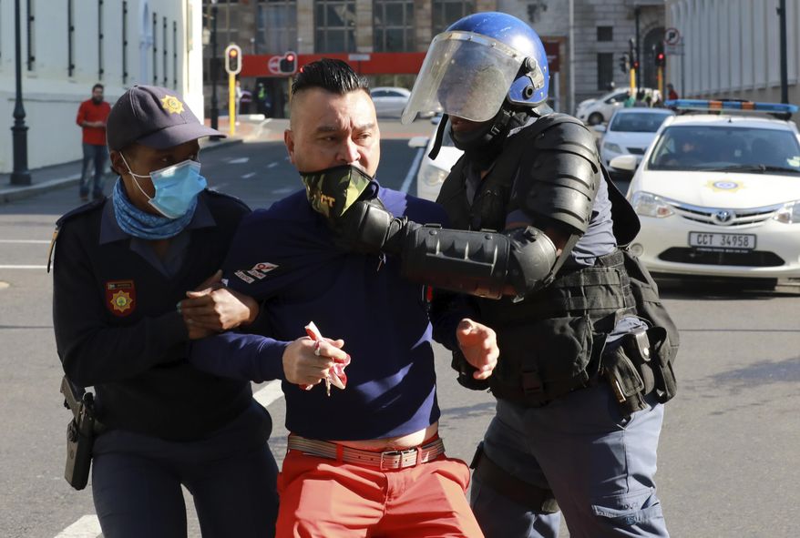 A demonstrator working in the hospitality industry is arrested by police during a protest against lockdown regulations in the streets close to Parliament in Cape Town, South Africa, Friday July 24, 2020. People from various hospitality or restaurant establishments marched on parliament to raise awareness about the industry's declining revenues amid the Covid-19 lockdown. (AP Photo/Nardus Engelbrecht)